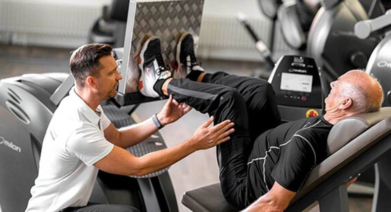 Mann trainiert mit Trainer im Fitnessstudio.